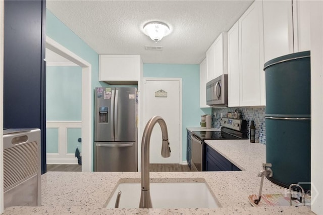 508 Pointe S Dr, Savannah, GA 31410 - kitchen featuring stainless steel appliances, light stone counters, white cabinets, a textured ceiling, and backsplash