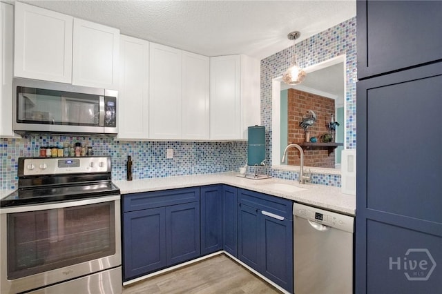 508 Pointe S Dr, Savannah, GA 31410 - kitchen with stainless steel appliances, white cabinetry, tasteful backsplash, blue cabinetry, and a textured ceiling