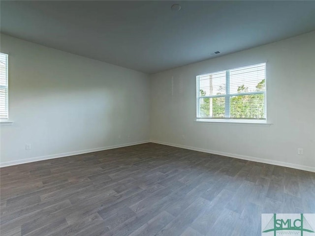 empty room with dark wood-style floors and baseboards
