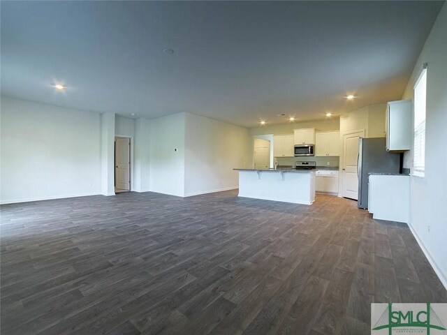 unfurnished living room with dark wood-style floors, baseboards, recessed lighting, and a sink