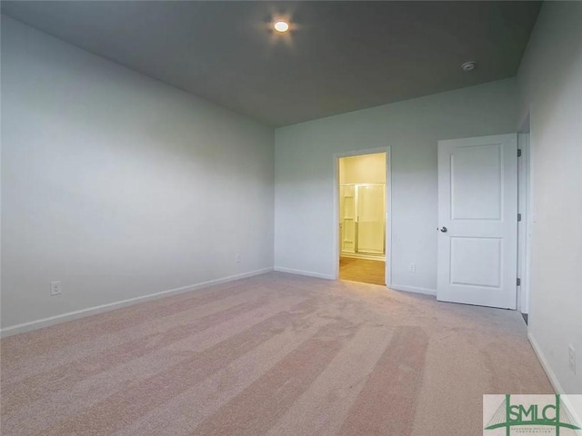 unfurnished bedroom featuring light colored carpet, baseboards, and ensuite bathroom