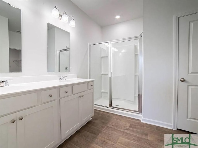 full bath featuring a shower stall, wood finished floors, and double vanity