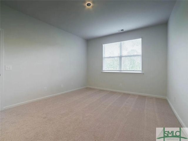 spare room with light colored carpet and baseboards