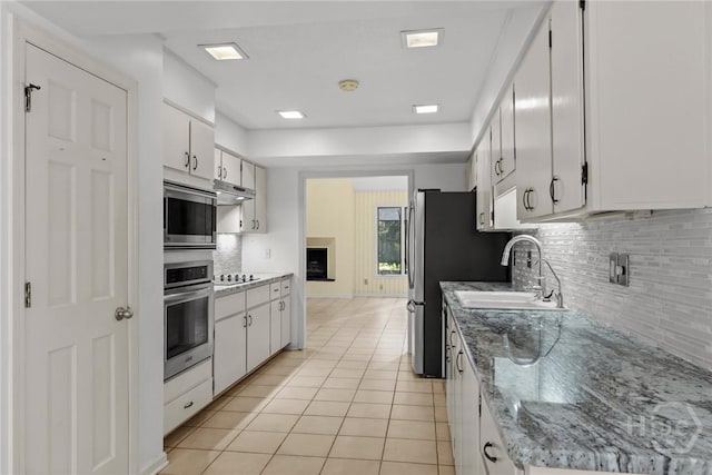 2402 Easy St, Savannah, GA 31406 - kitchen featuring stainless steel appliances, a sink, under cabinet range hood, light tile patterned floors, and decorative backsplash