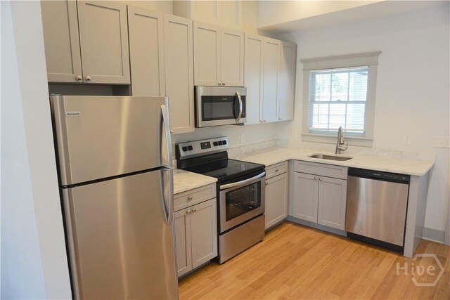 514-516 E Hall St, Savannah, GA 31401 - kitchen featuring stainless steel appliances, a sink, light wood-style flooring, gray cabinets, and light stone countertops