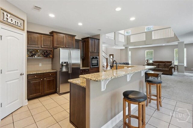 525 Elkins Cemetery Rd, Guyton, GA 31312 - kitchen with stainless steel refrigerator with ice dispenser, a kitchen bar, light tile patterned floors, open floor plan, and light colored carpet
