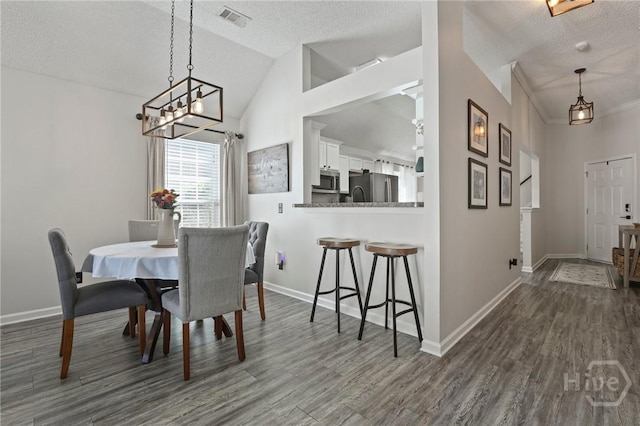 dining area with a textured ceiling, dark wood-style flooring, baseboards, a chandelier, and lofted ceiling