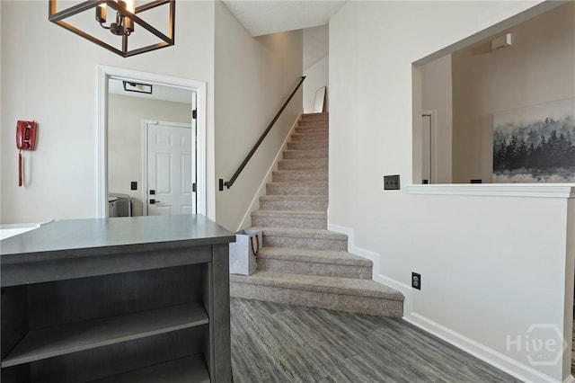 stairs featuring baseboards, wood finished floors, and a chandelier