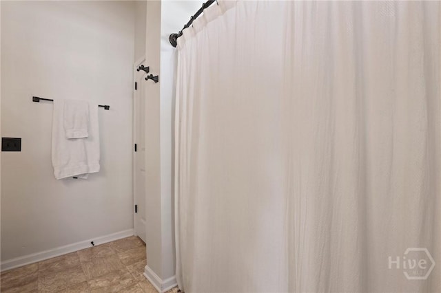 full bathroom with baseboards and a shower with shower curtain