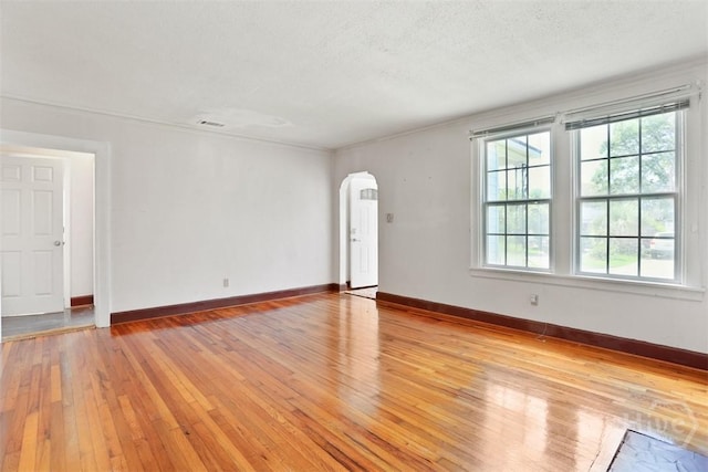 2120 E 39th St, Savannah, GA 31404 - unfurnished living room with arched walkways, light wood-style floors, baseboards, crown molding, and a textured ceiling