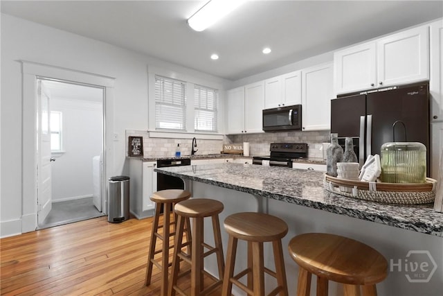 1216 E 31st St, Savannah, GA 31404 - kitchen featuring black microwave, range with electric stovetop, fridge with ice dispenser, a breakfast bar, and tasteful backsplash