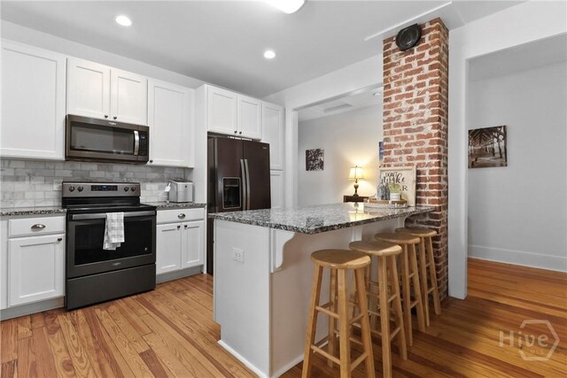 1216 E 31st St, Savannah, GA 31404 - kitchen with electric range, stainless steel microwave, light wood-style flooring, dark stone countertops, and recessed lighting