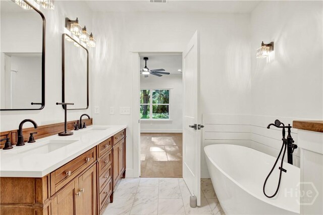bathroom featuring a freestanding tub, double vanity, marble look tiles, and a ceiling fan