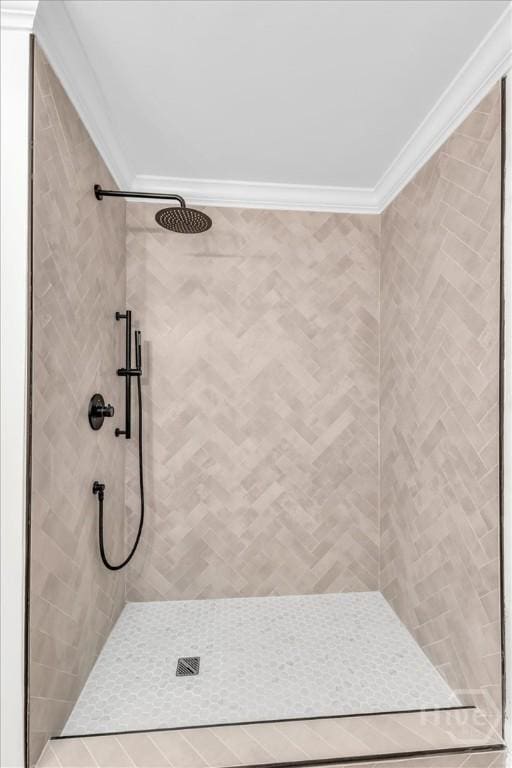 bathroom with ornamental molding and a tile shower