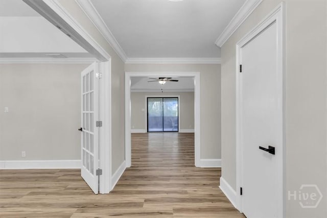 corridor with light wood finished floors, baseboards, and crown molding