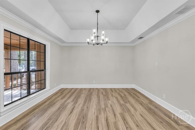 empty room with light wood-style flooring, a chandelier, baseboards, crown molding, and a raised ceiling