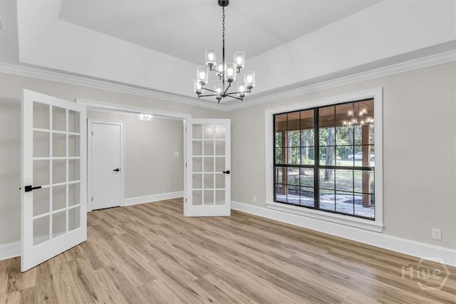 spare room featuring french doors, a chandelier, wood finished floors, crown molding, and baseboards