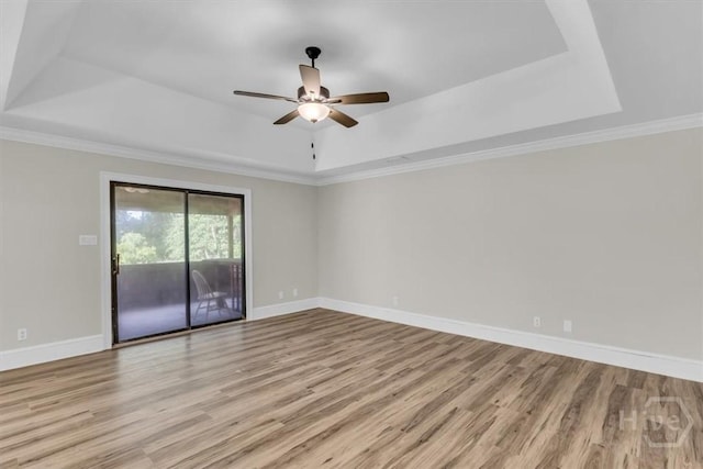 unfurnished room with a raised ceiling, wood finished floors, baseboards, a ceiling fan, and ornamental molding