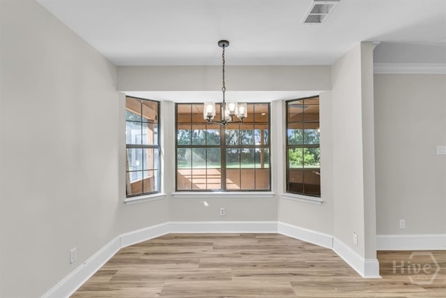 unfurnished dining area featuring a chandelier, healthy amount of natural light, wood finished floors, and baseboards