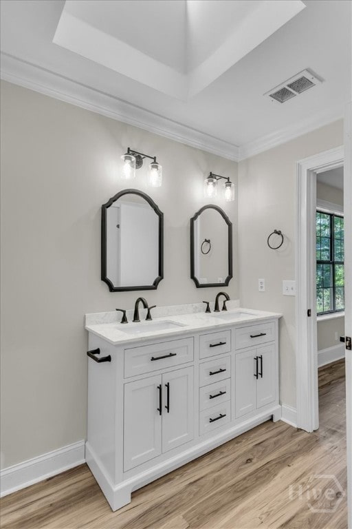 full bathroom with ornamental molding, wood finished floors, double vanity, and baseboards