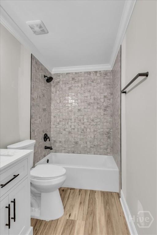 bathroom featuring wood finished floors, ornamental molding, shower / washtub combination, toilet, and vanity