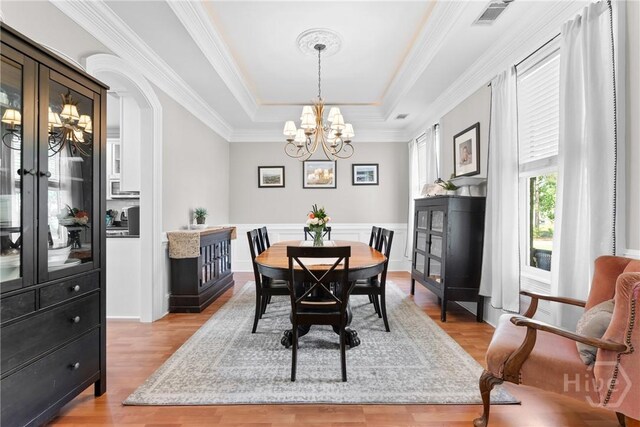 784 Ebenezer Rd, Rincon, GA 31326 - dining space featuring a chandelier, a raised ceiling, light wood-style flooring, ornamental molding, and arched walkways
