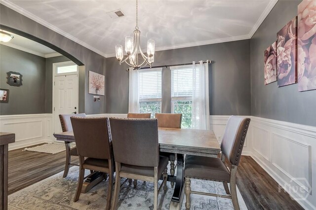 417 Keiffer Dr, Rincon, GA 31326 - dining area with arched walkways, dark wood finished floors, a decorative wall, a chandelier, and wainscoting