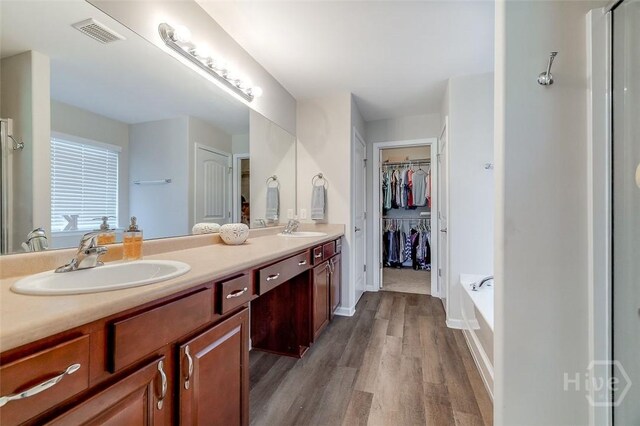 417 Keiffer Dr, Rincon, GA 31326 - bathroom with wood finished floors, a tub, double vanity, a walk in closet, and baseboards