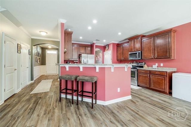 417 Keiffer Dr, Rincon, GA 31326 - kitchen featuring stainless steel appliances, arched walkways, a kitchen breakfast bar, ornamental molding, and light wood-type flooring