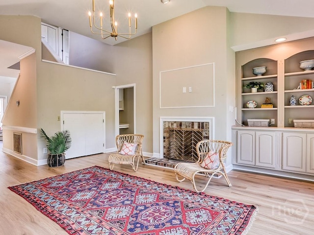 3 Riding Ln, Savannah, GA 31411 - sitting room with high vaulted ceiling, a brick fireplace, a chandelier, built in shelves, and light wood-style flooring