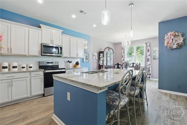 203 Merganser Dr, Pooler, GA 31322 - kitchen with appliances with stainless steel finishes, a sink, light wood-style flooring, a center island with sink, and white cabinets