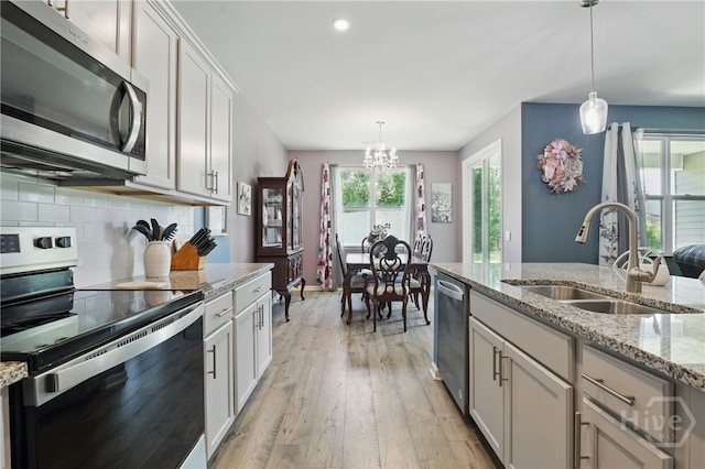 203 Merganser Dr, Pooler, GA 31322 - kitchen featuring stainless steel appliances, a sink, a chandelier, light wood finished floors, and decorative backsplash