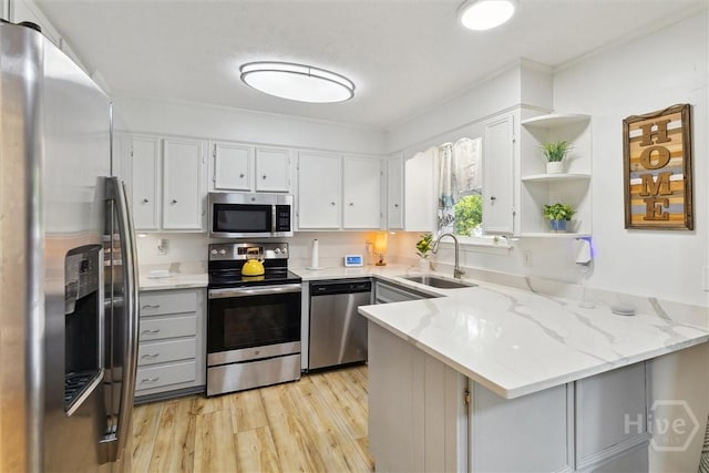 5633 Lafitte Dr, Savannah, GA 31406 - kitchen featuring appliances with stainless steel finishes, a sink, a peninsula, open shelves, and light wood-type flooring