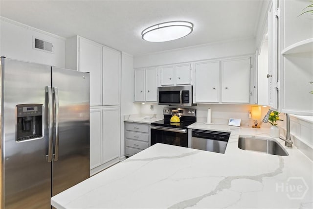 5633 Lafitte Dr, Savannah, GA 31406 - kitchen featuring appliances with stainless steel finishes, a sink, white cabinetry, light stone counters, and a peninsula