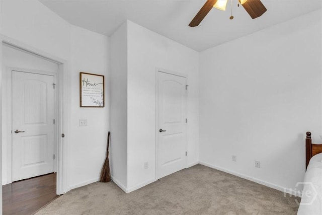 unfurnished bedroom with light colored carpet, baseboards, and a ceiling fan