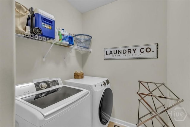 washroom featuring washer and clothes dryer and baseboards