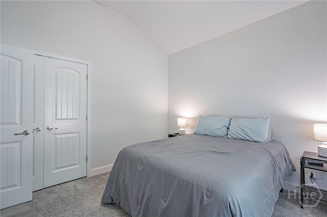 bedroom with light carpet, lofted ceiling, baseboards, and a closet