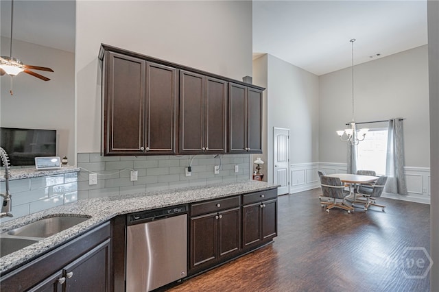 kitchen featuring stainless steel dishwasher, dark brown cabinetry, a ceiling fan, a sink, and a towering ceiling