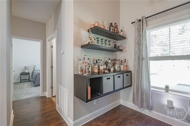 indoor dry bar with dark wood-style floors and baseboards
