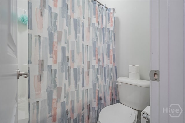 bathroom featuring toilet and curtained shower