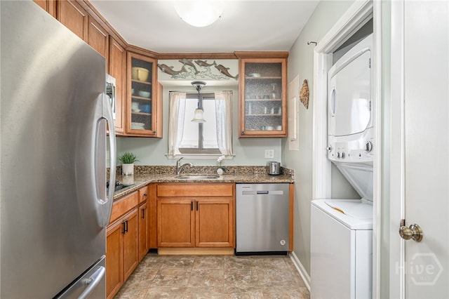 85 Van Horne Ave Unit 25C, Tybee Island, GA 31328 - kitchen featuring stainless steel appliances, stacked washer and clothes dryer, a sink, and brown cabinets