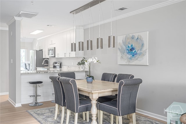 3005 River Dr Unit 209B, Savannah, GA 31404 - dining space featuring light wood finished floors, crown molding, and baseboards