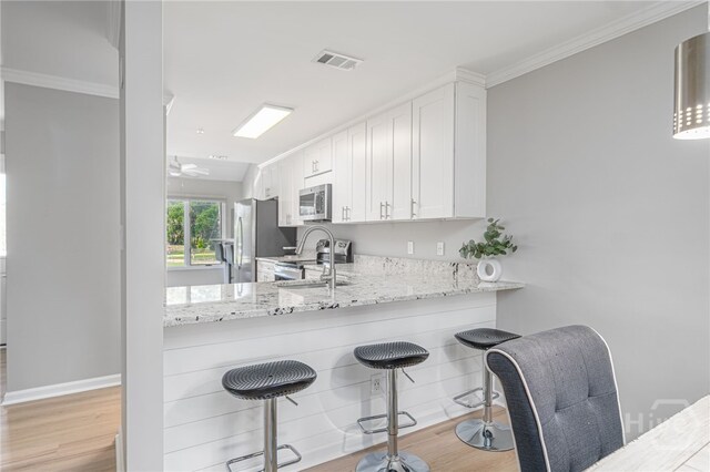 3005 River Dr Unit 209B, Savannah, GA 31404 - kitchen featuring appliances with stainless steel finishes, light wood-style flooring, white cabinets, and ornamental molding