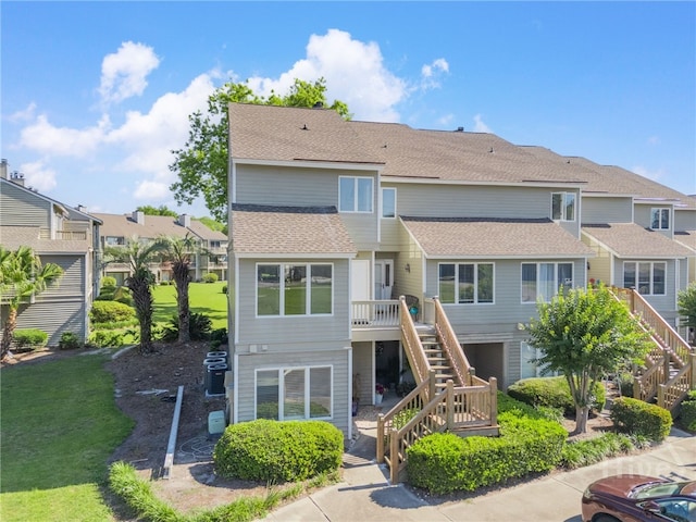3005 River Dr Unit 209B, Savannah, GA 31404 - rear view of house with stairway, a shingled roof, a residential view, a wooden deck, and a lawn