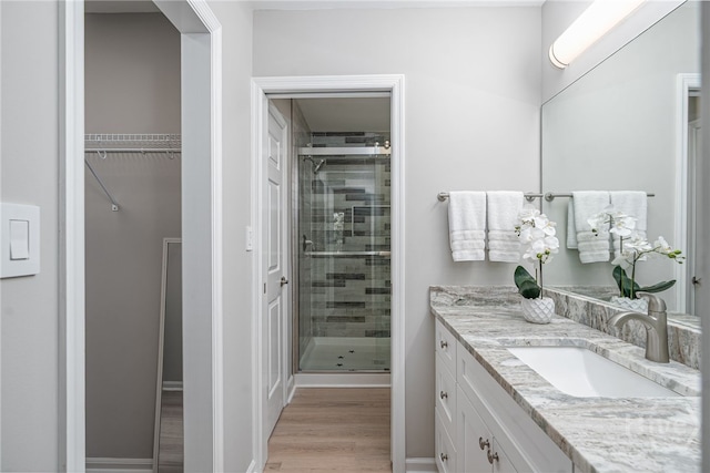 3005 River Dr Unit 209B, Savannah, GA 31404 - bathroom featuring a stall shower, vanity, wood finished floors, and a spacious closet