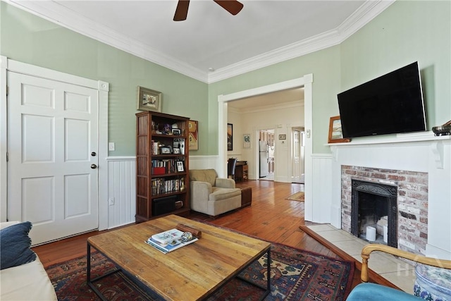542 E Gaston St Unit A, Savannah, GA 31401 - living room featuring wood finished floors, ceiling fan, crown molding, a wainscoted wall, and a brick fireplace