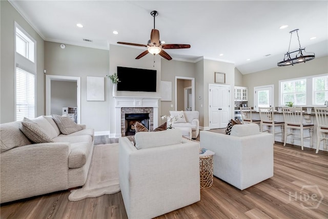 living area featuring ornamental molding, a ceiling fan, a high ceiling, a fireplace, and wood finished floors
