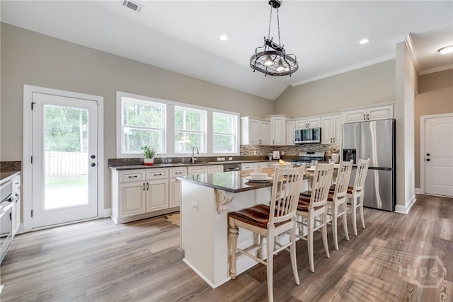 kitchen with stainless steel appliances, a sink, crown molding, tasteful backsplash, and a kitchen breakfast bar