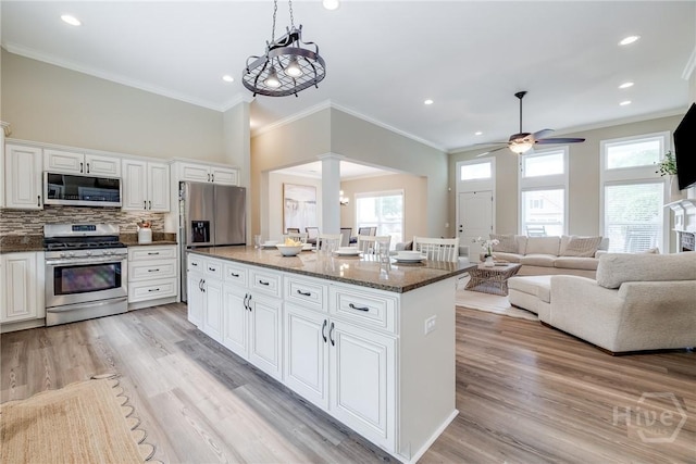 kitchen with stainless steel appliances, ornate columns, plenty of natural light, a ceiling fan, and crown molding