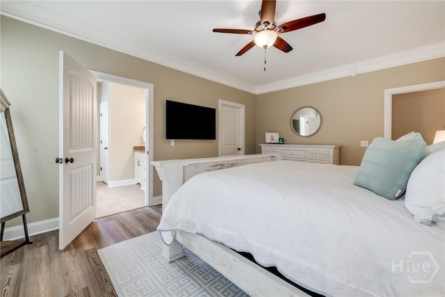 bedroom featuring crown molding, wood finished floors, baseboards, ensuite bath, and ceiling fan